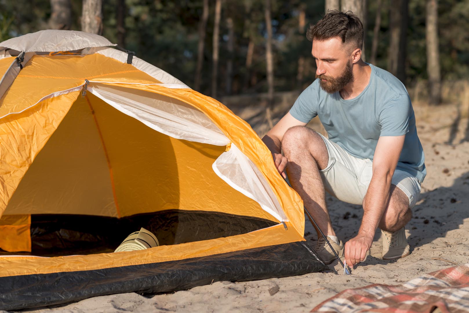 Crouching man setting up tent