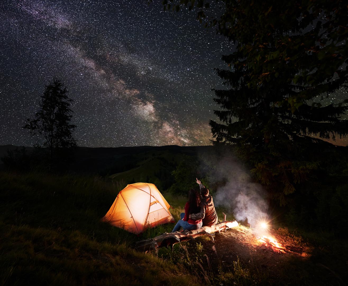 Man pointing incredible beautiful starry sky milky way couple sitting near glowing