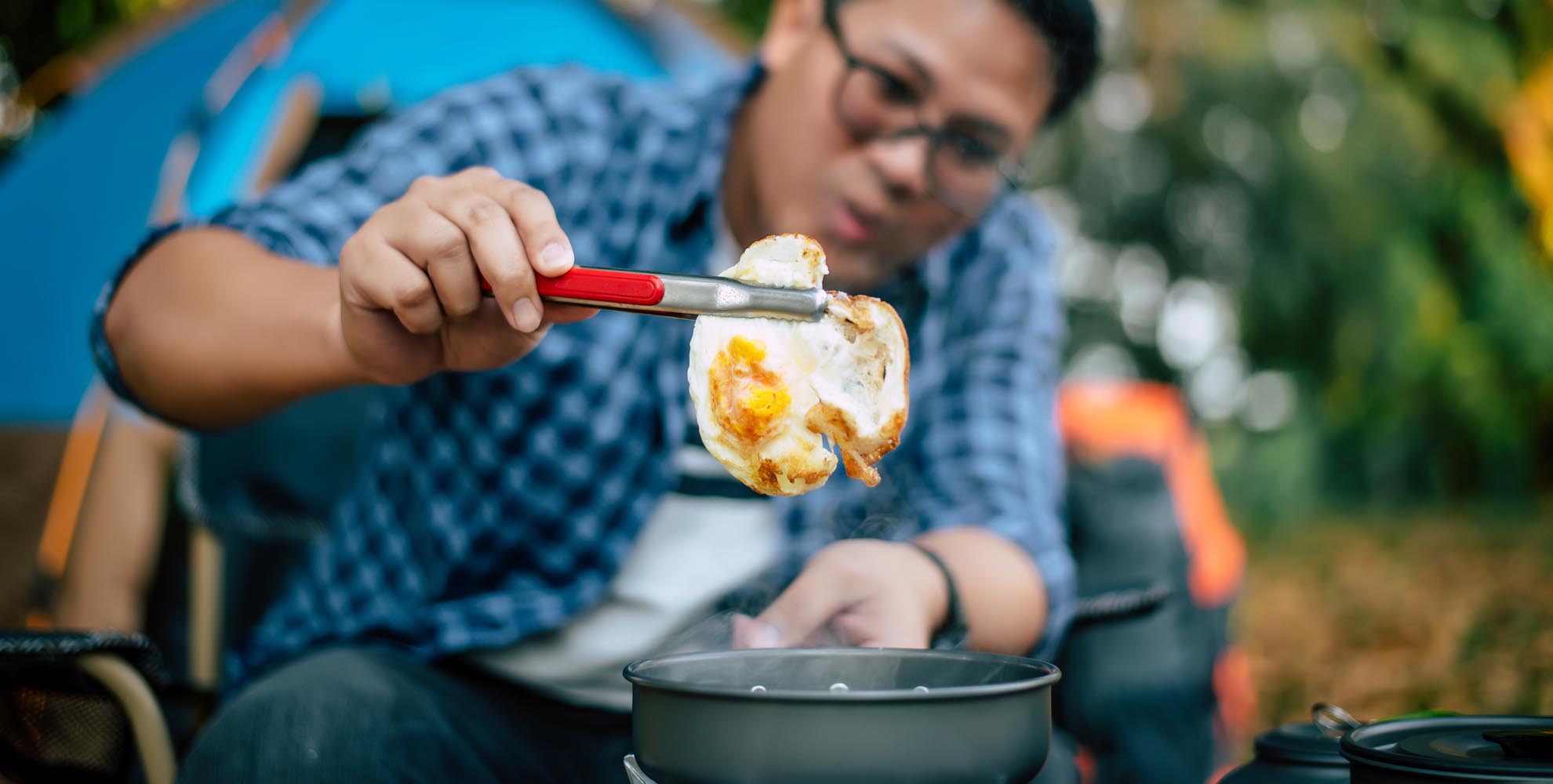 Portrait asian traveler man glasses frying tasty fried egg hot pan campsite