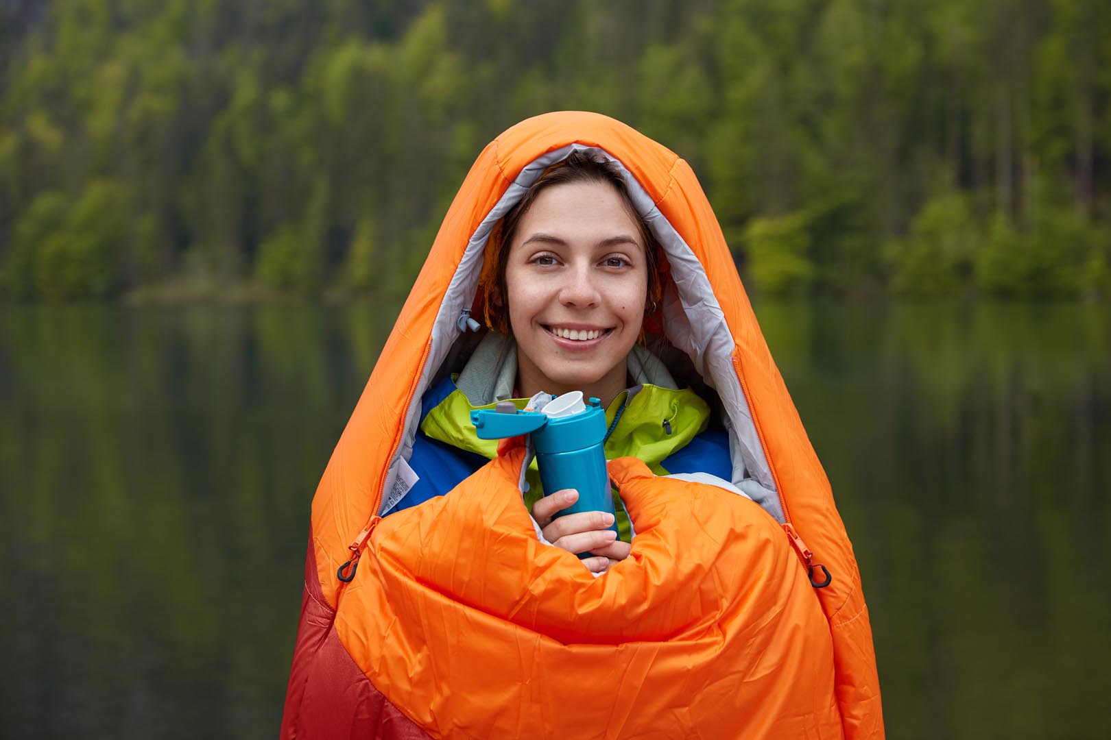 Smiling female traveler being good mood wrapped sleeping bag spends free time