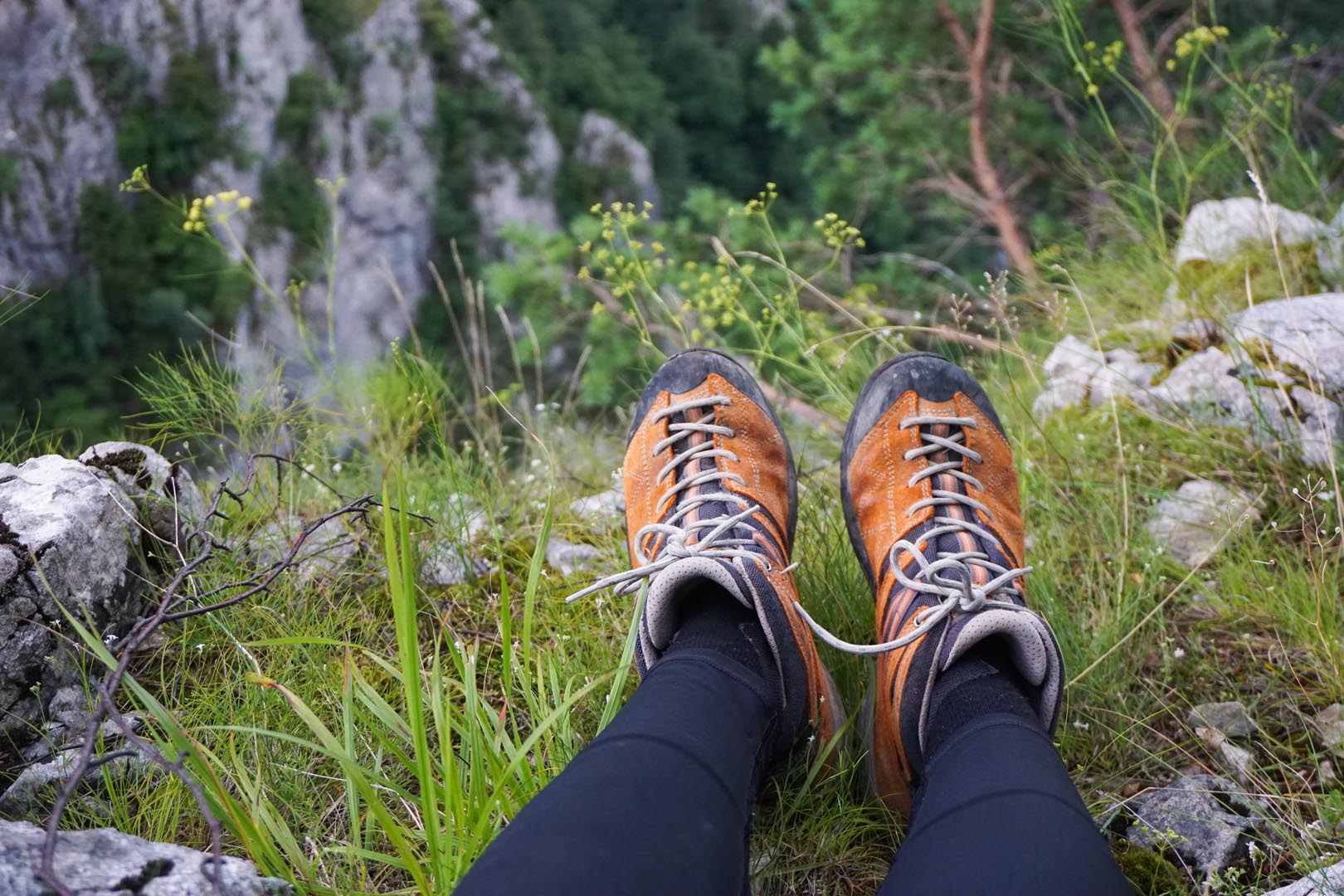 Stunning shot person sitting terrain grass rocks flowers camping ground