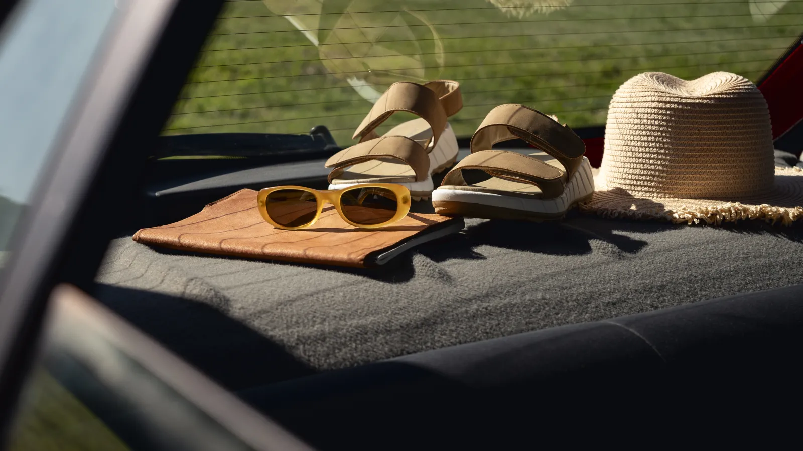 Straw hat, sunglasses and sandals laid out on the back of a car
